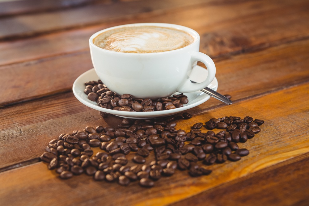 Cappuccino with coffee beans on table in cafeteria.jpeg